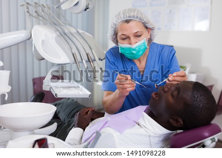 Dentist professional filling teeth for man patient sitting in medical chair 
