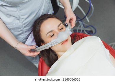 dentist puts inhalation sedative mask on his patient. - Shutterstock ID 2148086555