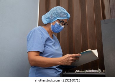 Dentist Reviewing Files From A Filing Cabinet In A Clinic. Files In Filing Cabinet