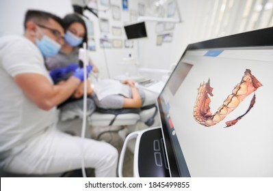 Dentist Scanning Patient's Teeth With Modern Scanning Machine. Digital Print Of Patient's Teeth Is On Big Screen. Modern High Precision Technologies. Concept Of Modern Dentistry