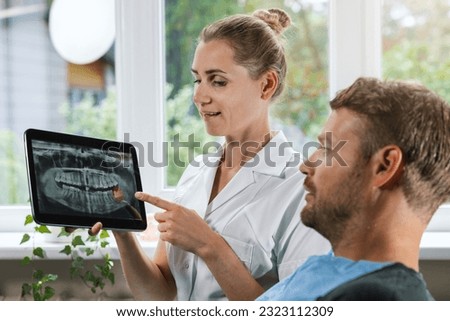dentist showing and explaining dental x-ray picture with impacted wisdom tooth to his patient