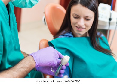 Dentist Showing To His Patient A Dental Implant With Crown