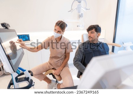 Dentist showing multidimensional image to patient sitting on a chair in a modern clinic