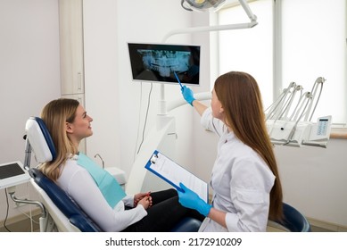 Dentist showing patient jaw teeth x-ray image. Doctor and woman client during consultation at dental clinic. Issues discussing. Medical healthcare and stomatological help. Professional appointment - Shutterstock ID 2172910209