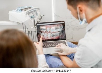 Zahnarzt, der während einer kieferorthopädischen Behandlung ein Foto der Zähne auf einem Monitor für einen jungen Patienten zeigt. Mädchen, die sich mit einem Kieferorthopäden beraten. Hochwertiges Foto