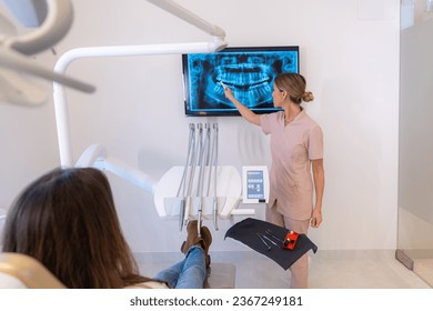 Dentist showing the results of the scan to a patient sitting on a chair in the clinic - Shutterstock ID 2367249181
