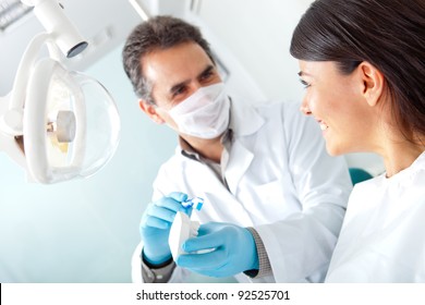 Dentist showing a woman how to brush her teeth on prosthesis - Powered by Shutterstock