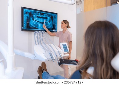 Dentist showing X ray image to patient sitting on a chair in the clinic - Shutterstock ID 2367249127