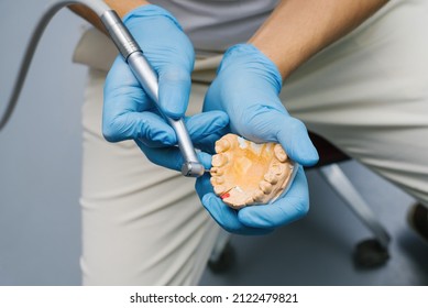 Dentist shows how to drill a tooth with a drill on a plaster model of a jaw with teeth - Shutterstock ID 2122479821