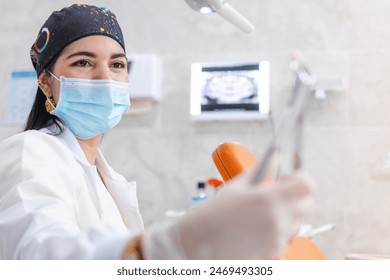 The dentist, specializing in root canal treatments, smiles as she examines a tooth she has removed from a patient and holds it with gripping forceps - Powered by Shutterstock