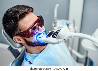 Dentist Starting Teeth Whitening Procedure With Young Man.