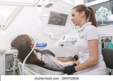 Dentist talking to her patient after putting inhalation sedation face mask on her - Shutterstock ID 1890733858