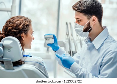 Dentist talking to his patient showing her dental mold. Side view. - Powered by Shutterstock