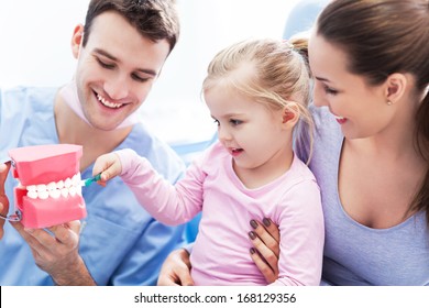 Dentist teaching girl how to brush teeth  - Powered by Shutterstock