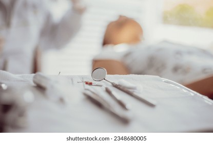 dentist tools on a table while he is checking a patient on the background - Powered by Shutterstock