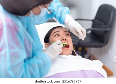 A dentist uses a dental floss holder to clean in-between the teeth of a female patient. After an oral prophylaxis procedure. At a dental clinic. - Powered by Shutterstock