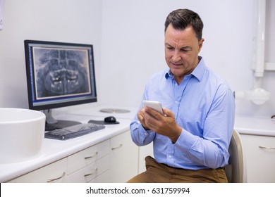 Dentist Using Mobile Phone In Clinic