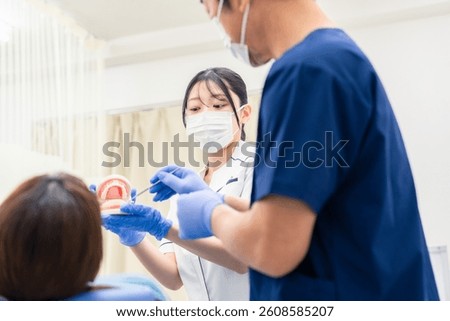 Dentist using a model of a tooth to explain dental treatment.