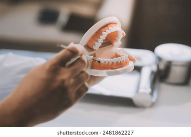 A dentist is using specialized dental equipment to inspect dentures to study the anatomy of the teeth before using the knowledge to treat patients, Dentures are being studied by oral specialists. - Powered by Shutterstock