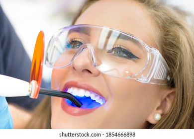 Dentist using ultraviolet lamp on a female patient
