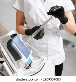 Dentist wearing white uniform and black gloves, working with all-in-one device concept for mechanical root canal treatment. Concept of modern dental endodontic equipment