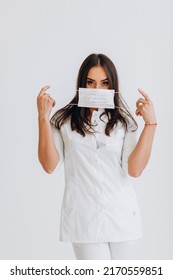 Dentist In White Coat And Glasses Stands Holding Mask Against Covid