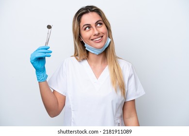 Dentist woman holding tools isolated on white background thinking an idea while looking up