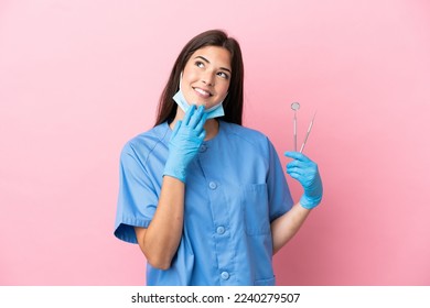 Dentist woman holding tools isolated on pink background looking up while smiling - Shutterstock ID 2240279507