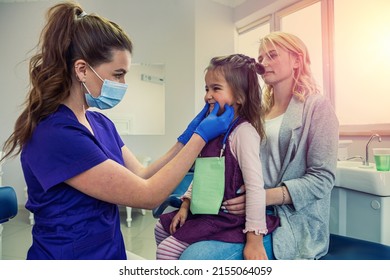 Dentist Woman In Medical Clothes Checks Teeth Of Baby Girl To Avoid Caries. The Concept Of Dentistry In Dentistry