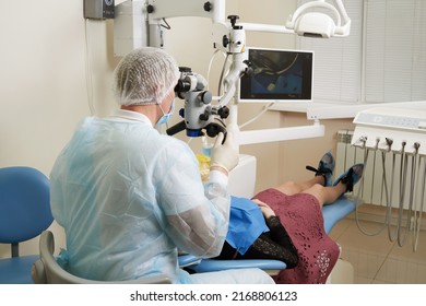 Dentist Working With Dental Microscope And Patient At Modern Dentist Clinic