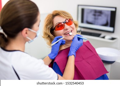 Dentist Working With Happy Female Patient At Modern Clinic