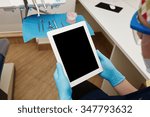 Dentist working on tablet pc at the dental clinic. White tablet with a blank screen