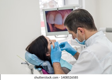 Dentist working with patient in dentist office - Shutterstock ID 1408526585