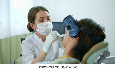 Dentist works, her patient in virtual reality glasses - Powered by Shutterstock