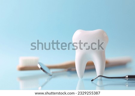Dentistry concept. Model of a tooth and dental instruments on a colored background with space for text. 
