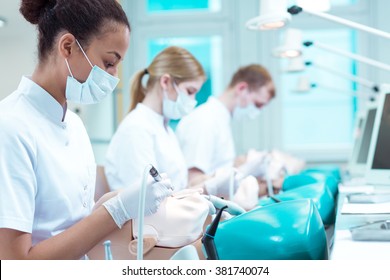 Dentistry Students In Medical Uniforms During Classes, Training On Manikins