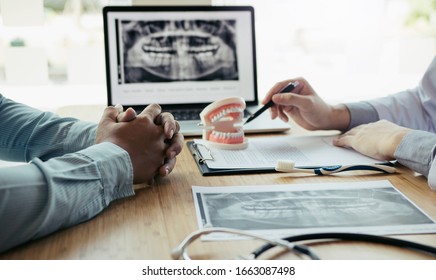Dentists are discussing dental problems at report x-ray image on laptop screen to patients. - Shutterstock ID 1663087498