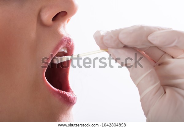 Dentist\'s Hand Taking Saliva Test From Woman\'s Mouth\
With Cotton Swab