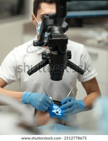 Dentist's work under microscope. Dental treatment using microscope. dentist treats isolated tooth using rubber dam under microscope. Dentist appointment. Dental equipment. Front view. 
