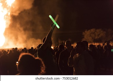 Denton, Texas / United States - November 10, 2017: University Of North Texas Students And Alumni With Green And White Glow Sticks Watching The Bonfire For Homecoming Week