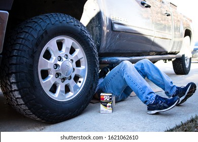 Denton, TX / USA - January 19, 2020: Man Lying Under A GMC 3/4 Ton Diesel Truck Changing The K&N Oil Filter In The Course Of A Do-it-yourself At Home Oil Change