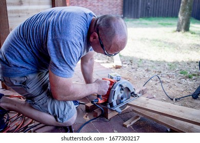 Denton, TX / USA - March 12, 2020: Closeup Of Caucasian Man In His Yard Cutting A 4x4 Wooden Post With An Electric Circular Saw For A DIY Project.