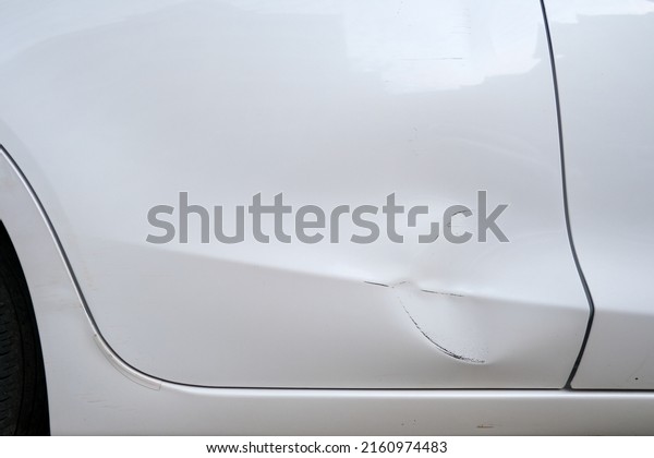 Dents on white car door  from an accident as\
concept insurance\
background