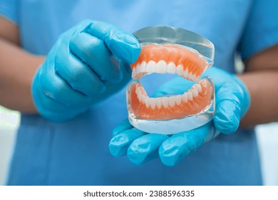 Denture, dentist holding dental teeth model to study and treat in hospital. - Powered by Shutterstock