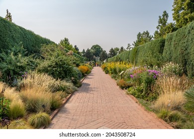 Denver, CO - August 30, 2021: People Visit The Botanic Gardens, Visible At The End Of A Long Pathway.