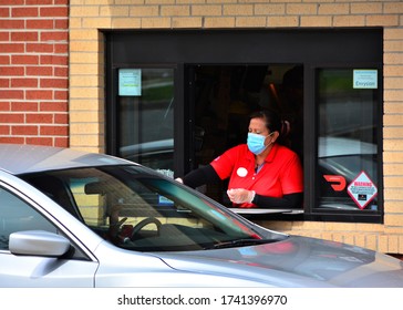 Denver, CO, USA. May 12, 2020. Fast food worker at Chick-Fil-A restaurant in Denver serving food to a drive thru customer while wearing her face mask. 