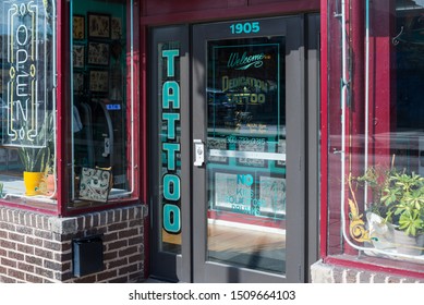 Denver, Colorado / United States of America - September 7 2019 : Dedication Tattoo store front and entrance.  Glass windows and doors, no kids, solicitors, or drunks.  neon open sign, off.