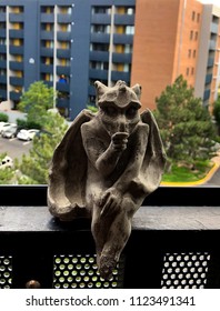 Denver, Colorado / United States - June 28, 2018:  Cast Stone Baby Goyle Thumb Sucker Sitting On Railing Of Apartment Balcony