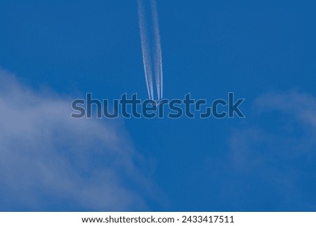 Departing and receding jet airliner with four engines in blue sky with clouds.