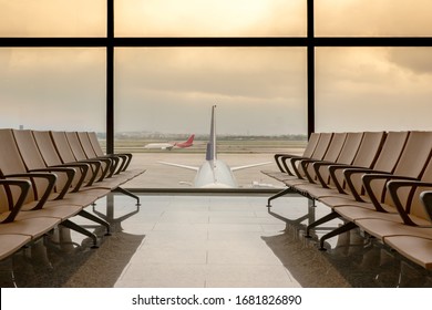 Départ du salon à l'aéroport avec des places en rang, avion et ciel rouge dramatique derrière les fenêtres.